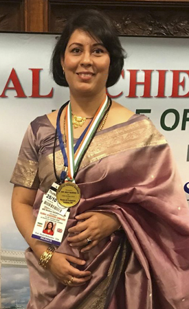 Professor Mahendra at ceremony, with a medal and lanyards around her neck