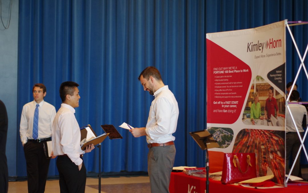 two men talking at a career fair in front of the Kimley Horn booth